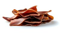 Thinly sliced pieces of dry-cured meat arranged in a stack showing texture and layers on white background, traditional charcuterie delicacy for gourmet appetizers.