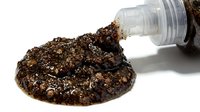 Exfoliating scrub with natural ingredients spilling from open jar, isolated on white background for cosmetic product packaging and skincare marketing.