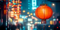 Red paper lantern glowing against blurred city lights at night creating warm festive atmosphere for celebrations and cultural events.