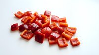 Fresh diced red bell pepper pieces isolated on white background ready for cooking and culinary preparations in kitchen recipes and healthy meal planning.