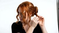 Young woman with long copper-red wavy hair styling her locks with hands against white background, suitable for beauty, haircare and lifestyle content.