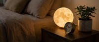 Cozy bedroom interior with glowing moon lamp on wooden nightstand creating warm ambient lighting atmosphere for relaxation and sleep.