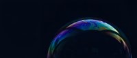 Iridescent soap bubble with rainbow colors floating against dark background for creative design projects and artistic compositions.
