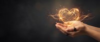 Hand holding glowing golden heart with light particles and sparkles on dark background, symbolizing love, care, and compassion for design use.
