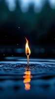 Burning match standing in water with orange flame reflection, dramatic dark blue background with bokeh lights creates surreal atmosphere for conceptual designs.