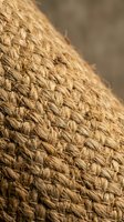 Natural jute rope coil close-up showing detailed fiber texture and weaving pattern for rustic home decor and craft projects.