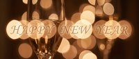 Champagne flutes glowing against warm bokeh lights with Happy New Year text, perfect for festive greeting cards and holiday celebrations.