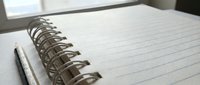 Open spiral notebook with lined pages and pen ready for writing notes, planning, journaling or creative work on desk near window with natural light.
