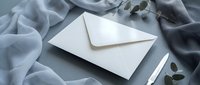 Elegant white envelope on soft gray fabric with eucalyptus leaves for wedding invitations, correspondence, stationery design and luxury branding projects.