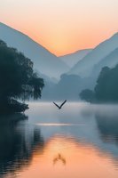 Serene mountain lake at dawn with bird flying over misty water, surrounded by silhouetted hills and trees reflecting golden sunrise colors in calm surface.