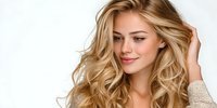 Young blonde woman with wavy hair touching her head, smiling softly against white background. Natural beauty portrait for skincare and haircare campaigns.