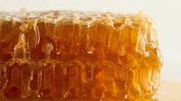 Fresh golden honeycomb dripping with pure honey on white background. Natural organic sweetener for healthy eating and cooking applications.