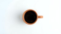 Orange ceramic coffee mug with black coffee viewed from above on white background, isolated for design use in branding and promotional materials.