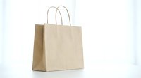 Brown kraft paper shopping bag with twisted handles isolated on white background for retail packaging and eco-friendly commercial use.