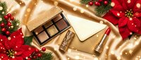 Luxury chocolate gift box with golden ribbon surrounded by festive decorations, pine branches and warm lights creating elegant holiday atmosphere.