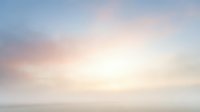 Serene dawn sky with soft pastel clouds transitioning from pink to blue over misty horizon, suitable for backgrounds and peaceful wellness content.