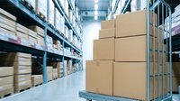 Cardboard boxes stacked on pallet in modern warehouse with shelving racks and inventory storage in background for logistics and supply chain.