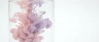 Abstract pink and purple ink swirls dissolving in clear water creating fluid organic shapes against white background for creative design projects.