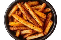 Roasted baby carrots seasoned with herbs and spices in dark ceramic bowl, top view. Fresh cooked organic vegetables with caramelized edges and golden color.