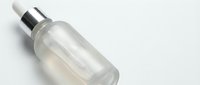 Clear glass dropper bottle with silver cap containing serum or oil on white background, isolated for skincare and cosmetic product design applications.