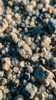 Close-up macro shot of natural mineral crystals and rough gemstones scattered on dark surface with shallow depth of field for geology education.