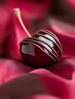 Dark chocolate truffle with elegant white chocolate drizzle resting on luxurious red silk fabric, macro shot highlighting glossy texture and gourmet detail.