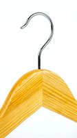 Wooden clothes hanger with chrome metal hook isolated on white background, closeup detail of natural wood grain texture for fashion retail.