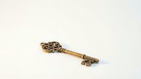 Ornate vintage brass key with decorative scrollwork handle isolated on white background for antique design projects and security concepts.