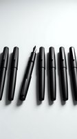 Black ink pens and fountain pen arranged in row on white background. Calligraphy and writing tools for art, design, education, and office use.