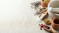 Natural herbs and spices in wooden bowls with mortar and pestle on linen background for cooking and seasoning culinary preparations.