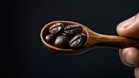 Fresh roasted coffee beans in wooden spoon against dark background, dramatic lighting highlights rich brown tones and natural textures. Close up macro shot.