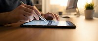 Professional using stylus pen on digital tablet at modern workspace desk for creative design work and digital art projects.