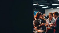 Business professionals networking at corporate conference event with modern lighting and casual conversation atmosphere for team building.