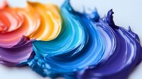 Vibrant rainbow acrylic paint swirls in blue, purple, orange and yellow creating colorful abstract texture for creative design projects.