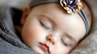 Peaceful sleeping baby with soft skin wearing gray headband with decorative flower, wrapped in cozy gray blanket. Close up portrait showing innocence and tranquility.