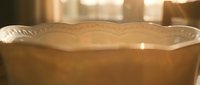 Empty vintage ceramic bowl with decorative rim on wooden surface in warm golden sunlight creating cozy kitchen atmosphere for food photography and culinary content.