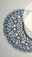 White decorative bowl casting intricate geometric shadow pattern on neutral surface creating artistic light and shadow composition for interior design.
