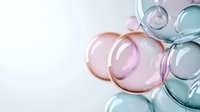 Delicate soap bubbles in soft pastel colors of pink, mint and blue floating against white background create dreamy ethereal composition with light reflections.