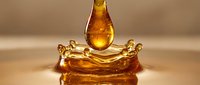 Golden honey drop falling into liquid pool, creating a crown splash with ripples, macro shot on warm beige background, natural organic sweetness.
