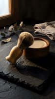 Traditional wooden shaving brush with soap bowl on dark slate surface creating vintage barbershop atmosphere for grooming and self-care concepts.