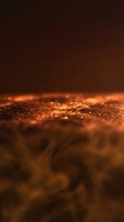 Macro shot of golden glitter particles with shallow depth of field and warm bokeh lighting against dark brown background, suitable for luxury, celebration, and festive design projects.