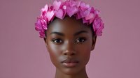 Young African American woman wearing pink heart-shaped flower crown against mauve background, natural makeup look and glowing skin, fashion portrait in soft lighting.