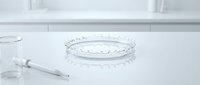 Petri dish with liquid droplets on white surface next to laboratory pipette for scientific research and medical testing.