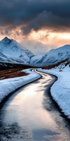 Winding mountain road through snow-covered landscape with dramatic stormy sky and golden sunset light illuminating distant peaks.