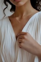 Close-up of Asian woman in pleated white dress with delicate gold necklace, capturing elegant bridal fashion details and romantic minimalist style.