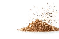 Scattered pile of crushed brown powder with fragments and particles spreading on white background, isolated product photography for cosmetic and food industry use.