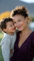 Tender moment between young mother and toddler son outdoors, sharing genuine smiles and warm embrace against soft natural background. Authentic family connection.