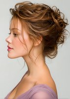 Side profile of young Caucasian woman with romantic messy updo hairstyle and natural makeup wearing pink dress against light background, beauty portrait.
