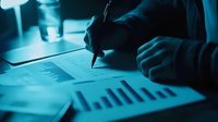 Business person analyzing financial data charts and graphs in dark blue lighting, working late on investment strategy report.