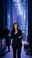 Professional businesswoman backstage at concert venue with dramatic purple lighting and technical equipment for entertainment industry presentations.